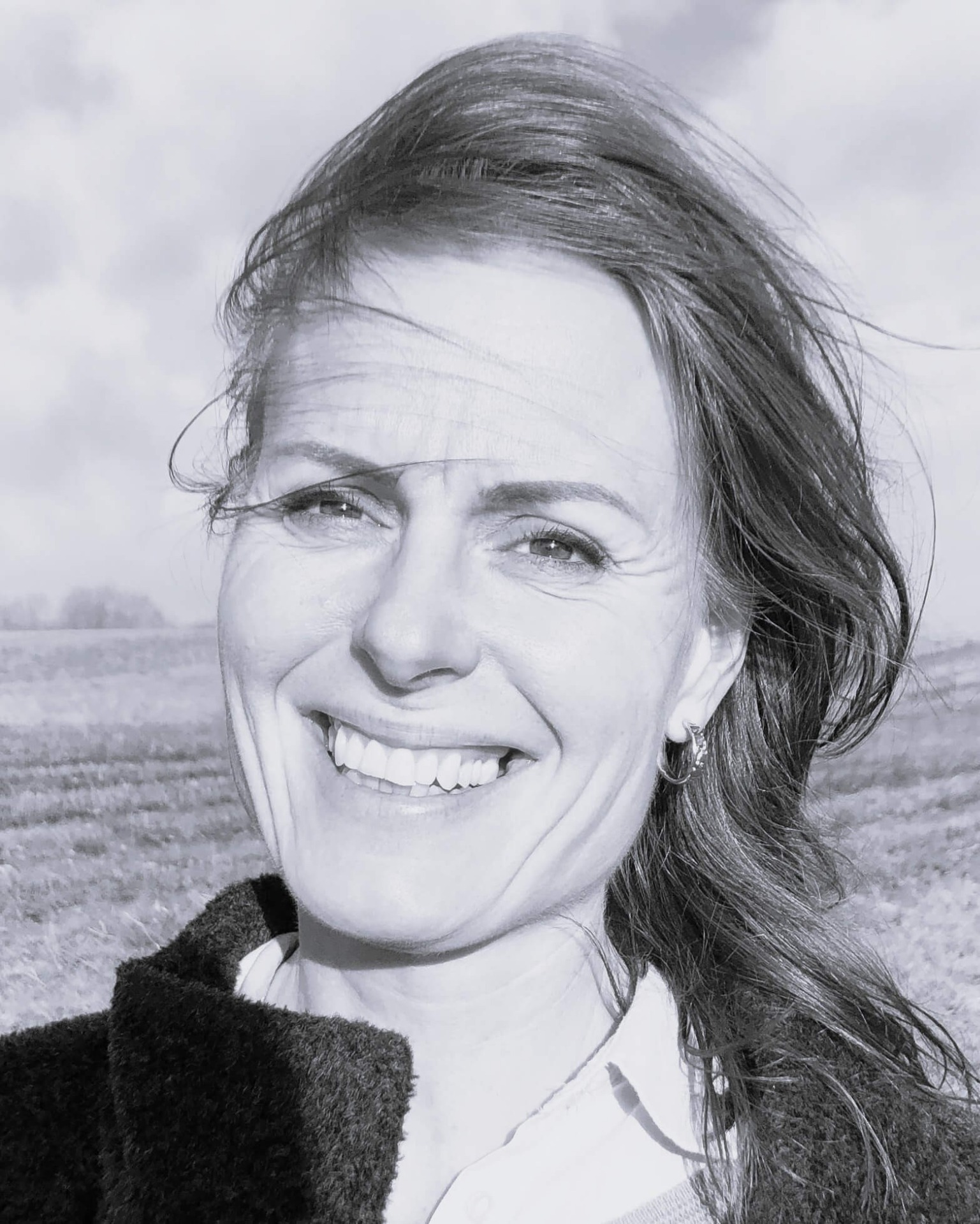 Sort/hvid nærbillede af smilende kvinde med vindblæst hår. Anette Werenskiold KlinkW
